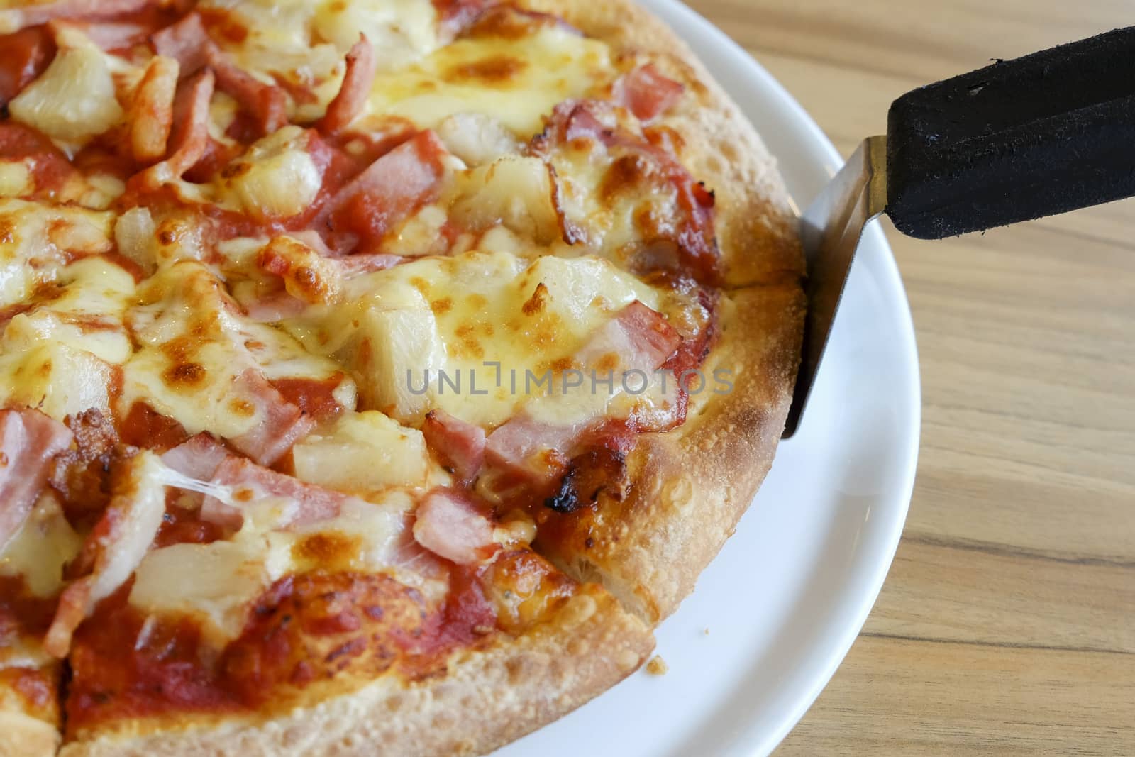 delicious hawaiian rustic style pizza made with fresh pineapples,ham and mozzarella cheese