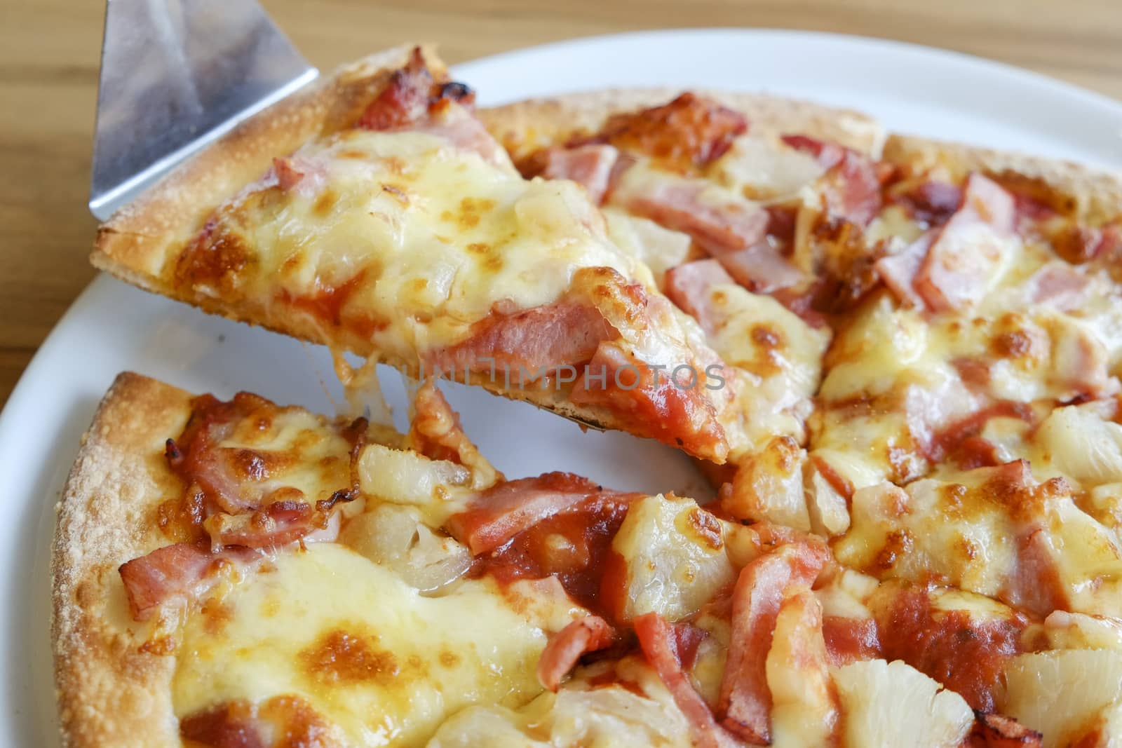 delicious hawaiian rustic style pizza made with fresh pineapples,ham and mozzarella cheese