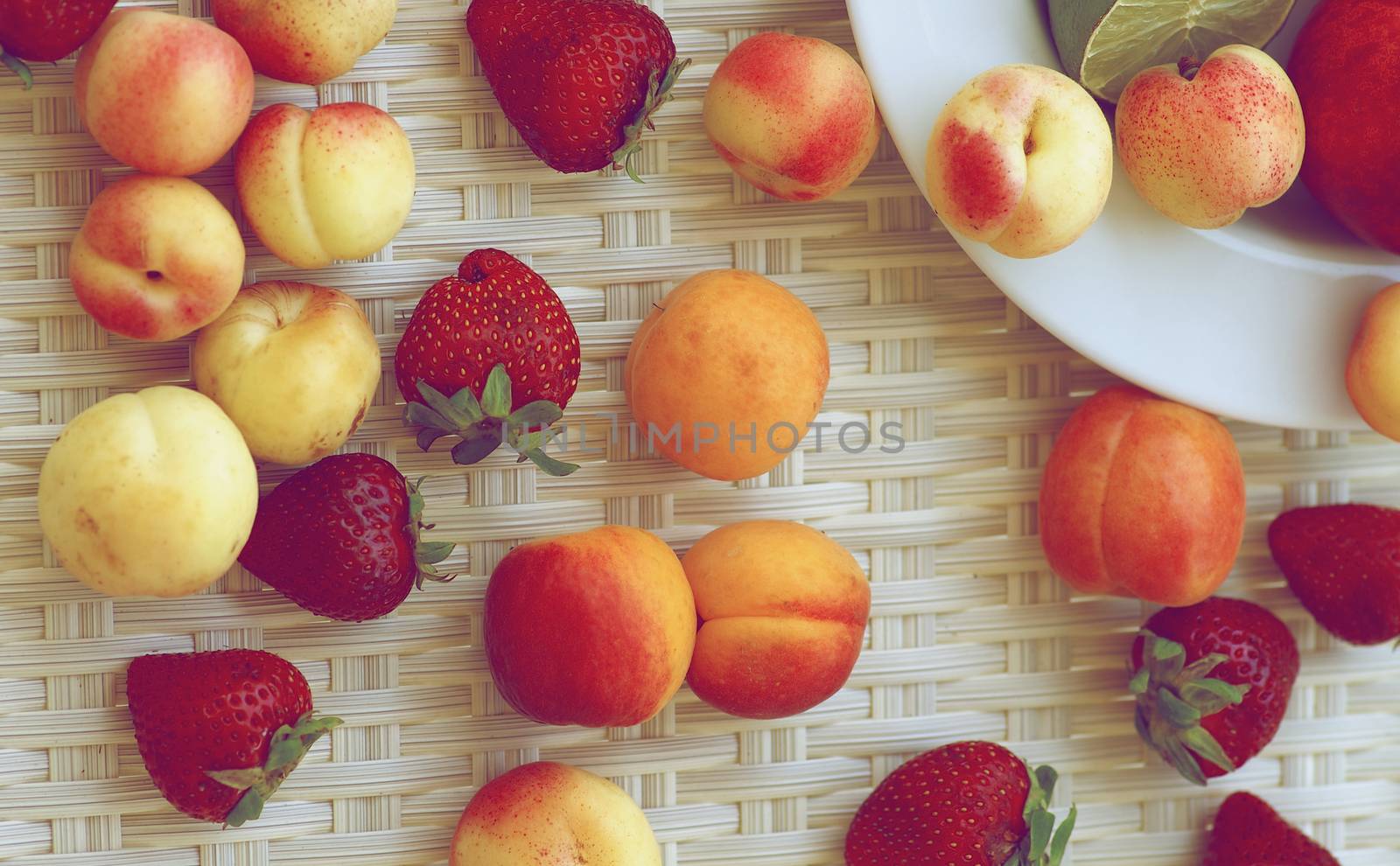 Fresh Ripe Apricots, Strawberries, Peaches, Nectarines and Lime closeup on White Wicker background. Retro Styled