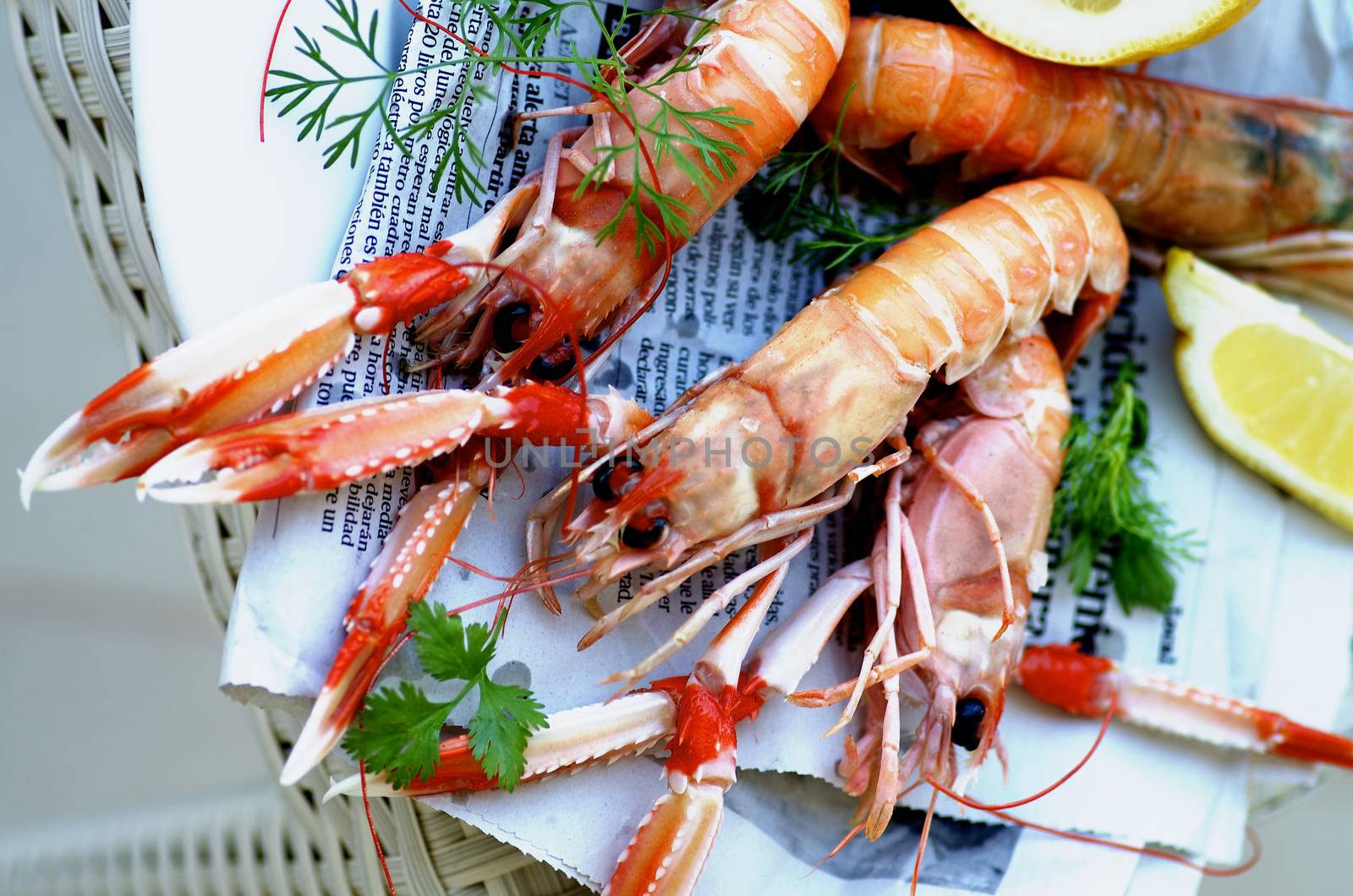 Delicious Grilled Langoustines with Lemon and Parsley on Newspaper closeup on Wicker background. Top View