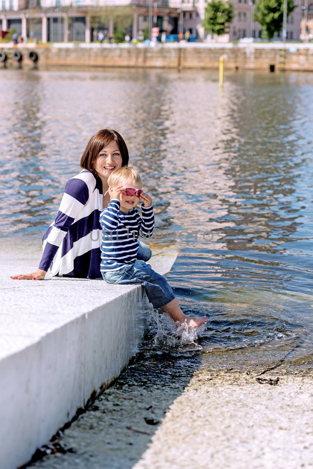 Lovely portrait of a mother and son outdoor playing on shore by Nanisimova