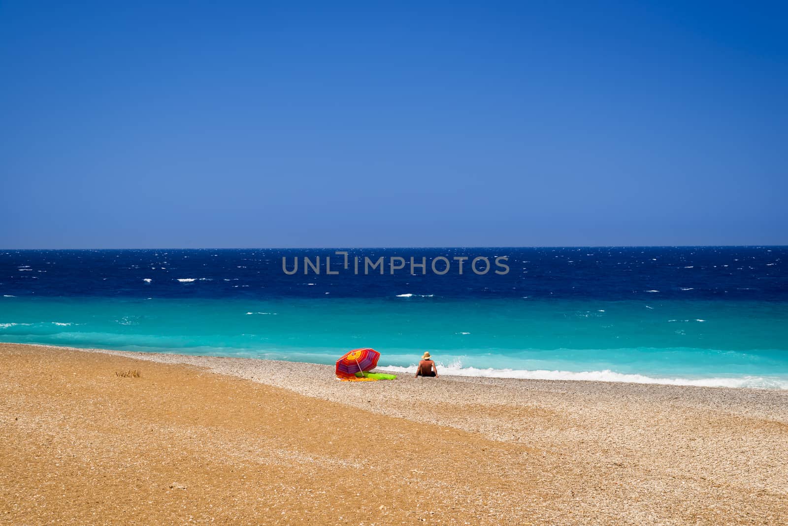 Sunbather calmly relaxing by the Deep Blue Seas at the North tip of Rhodes where the Aegean and Mediterranean Meet