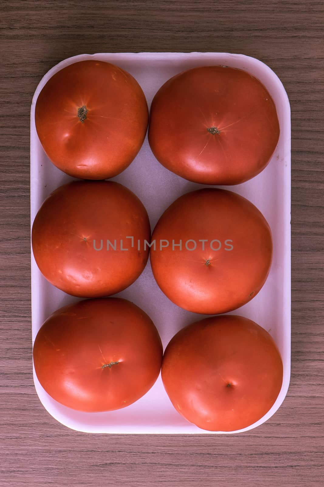 A big red tomatoes tray over wood
