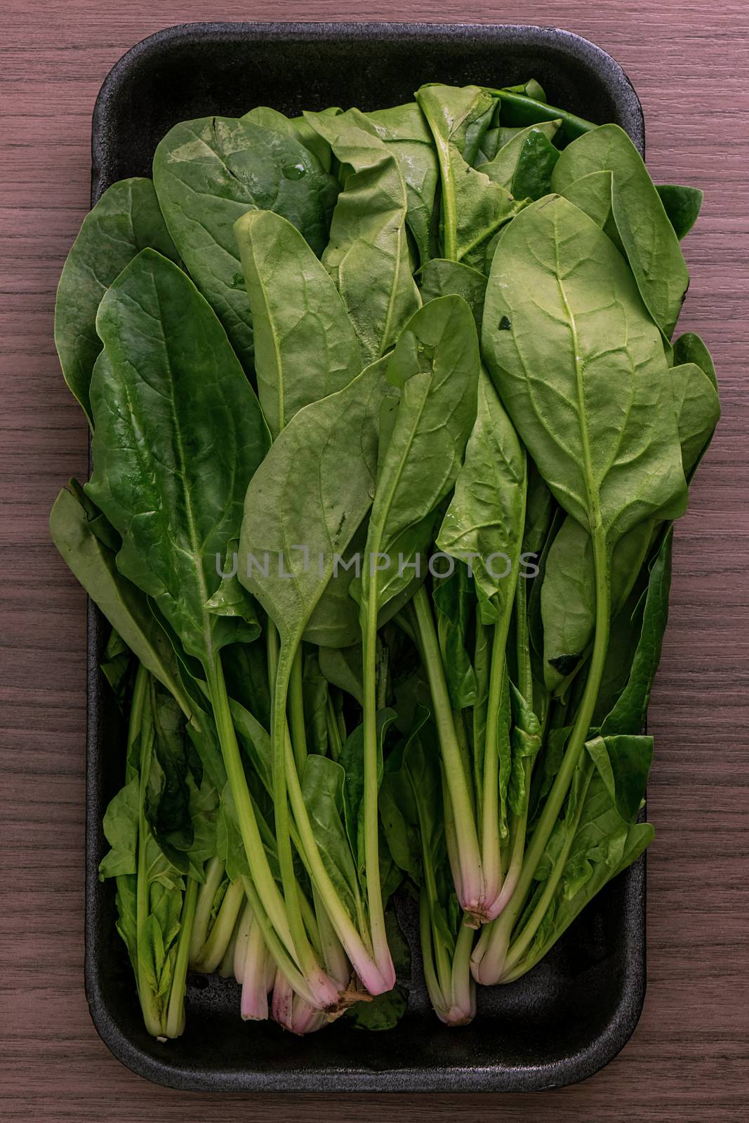 Some leafs of fresh green spinach over wood