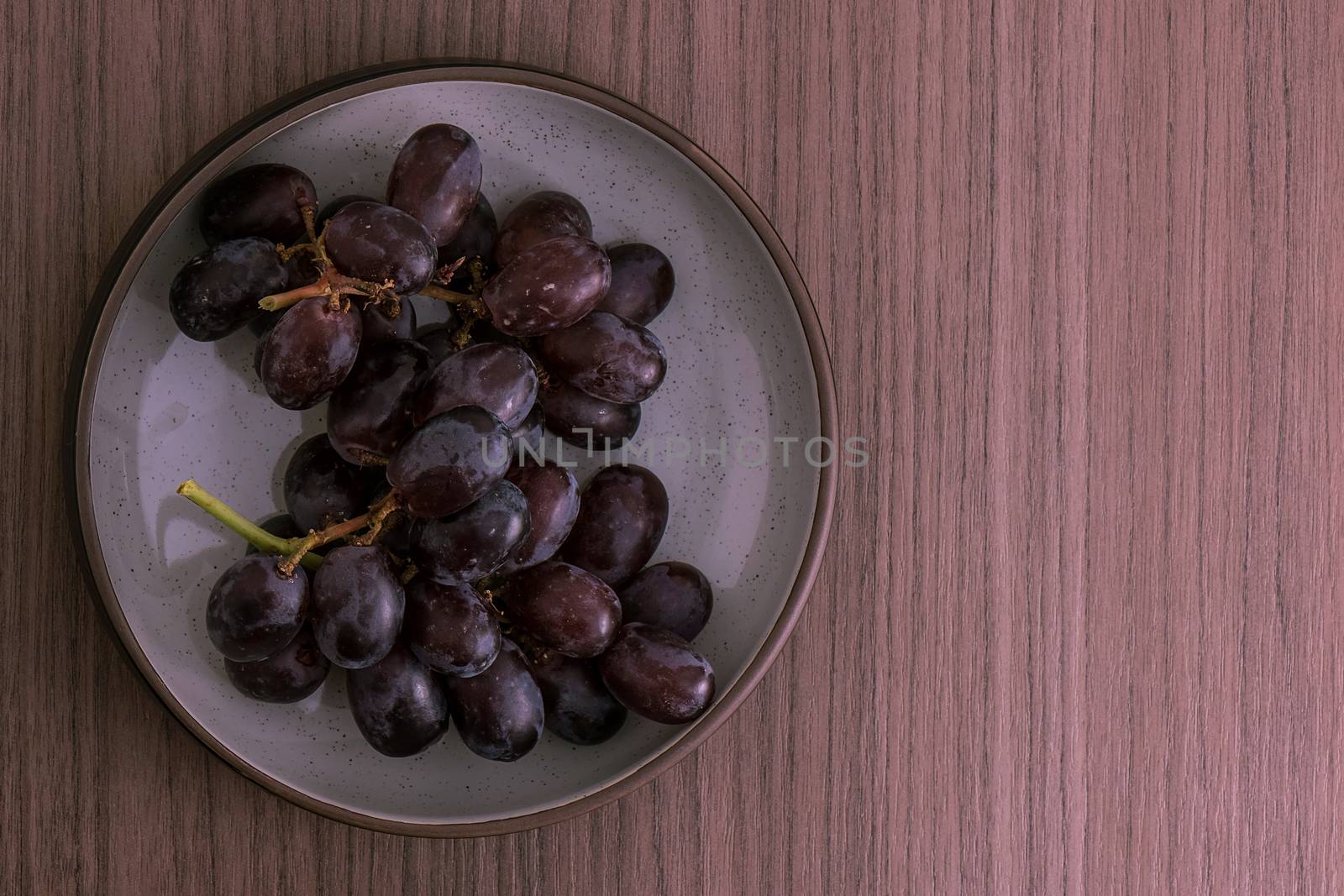 A bowl of red grapes over wood background