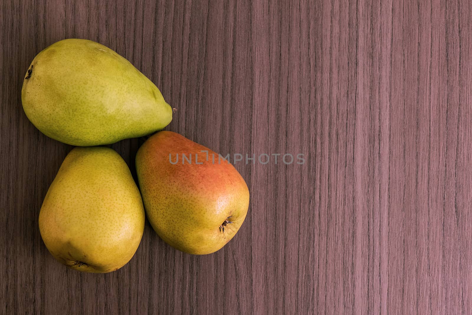 Three succulent ripe pears over wood background