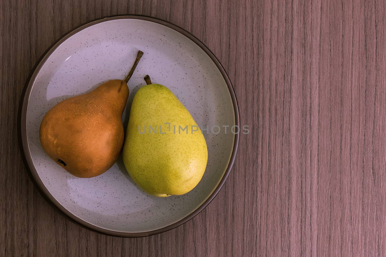 A bowl with a golden pear and a green pear