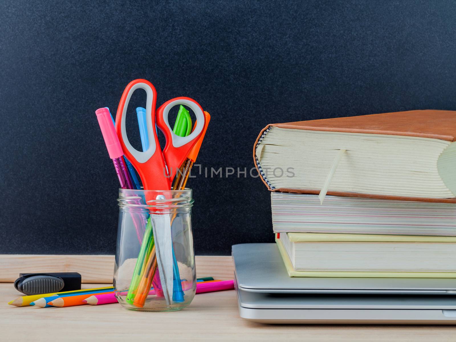 Back to school concept with school supplies laptop ,book, pen,mouse,and colored pencil on wooden table .