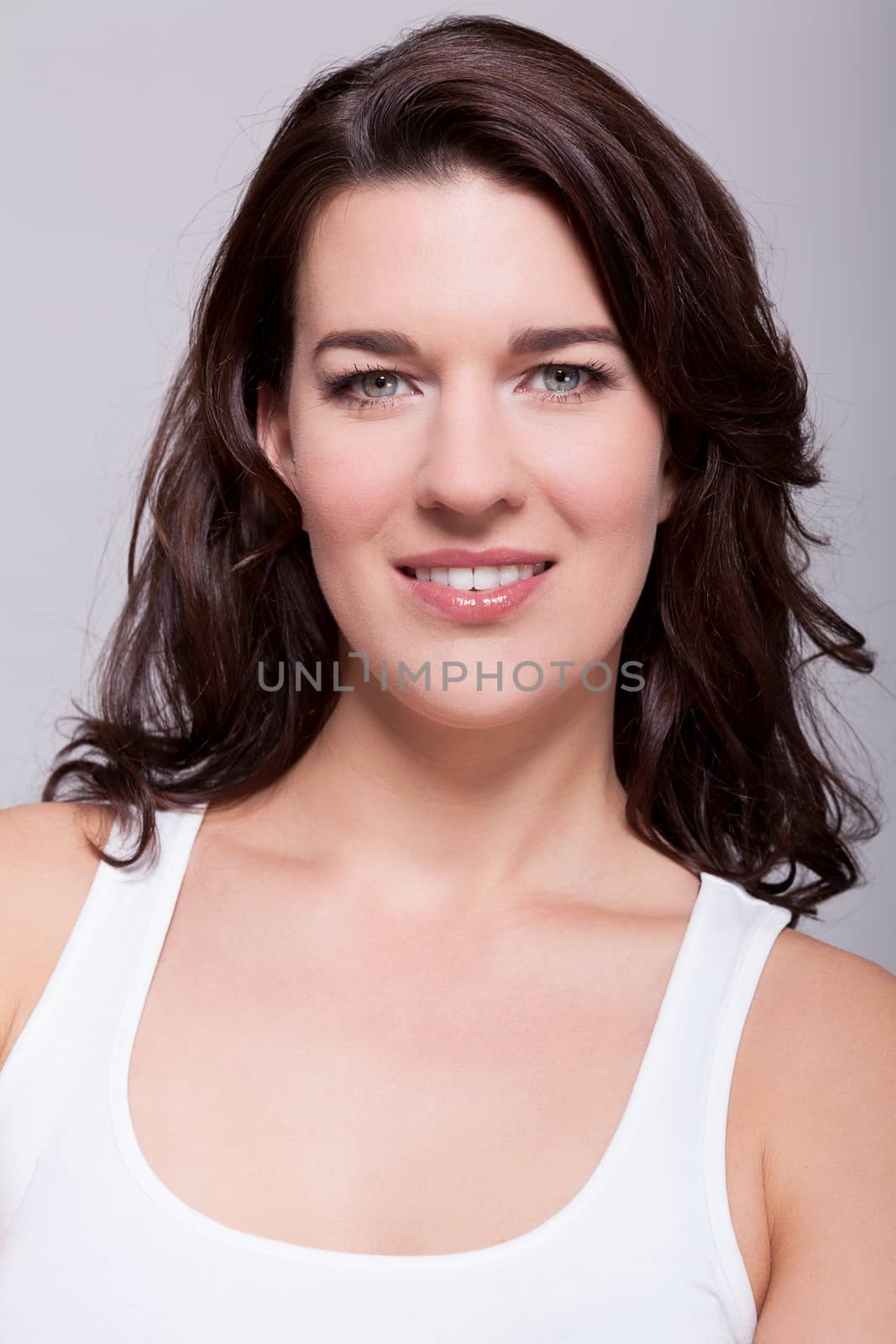 Portrait beautiful woman with dark hair smiling in the camera on grey background