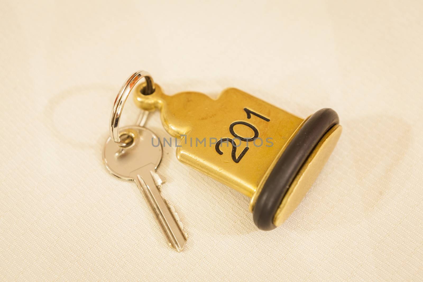 Hotel Room Key lying on Bed with keyring golden