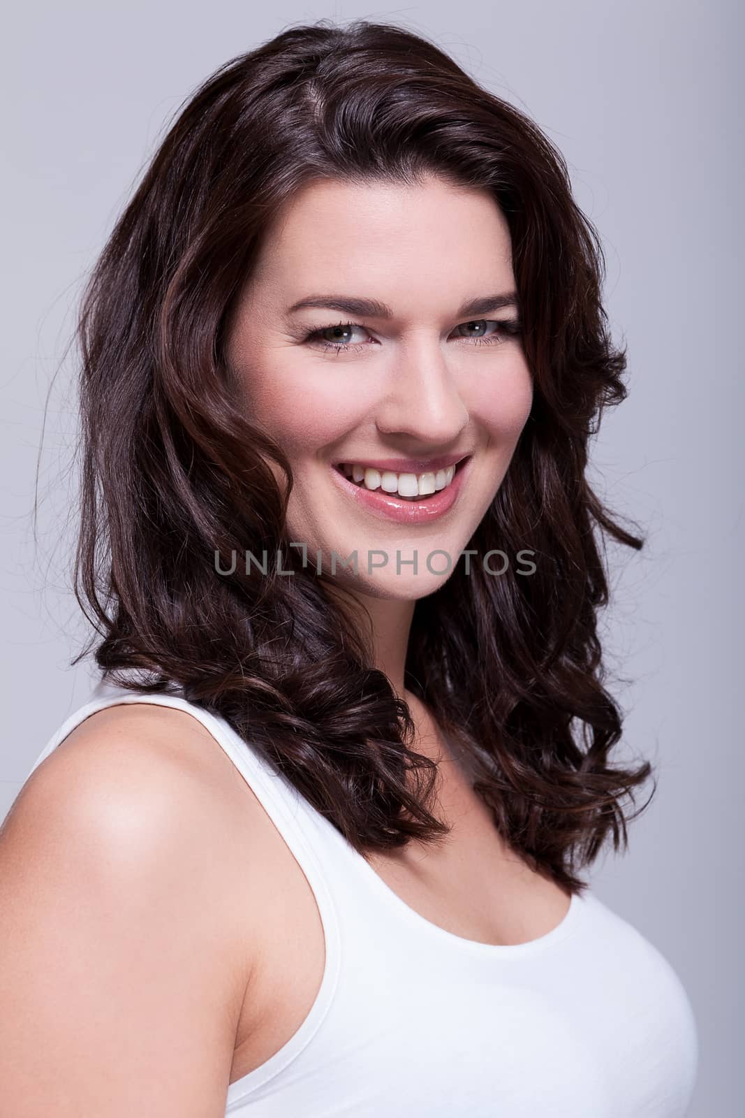 Portrait beautiful woman with dark hair smiling in the camera on grey background