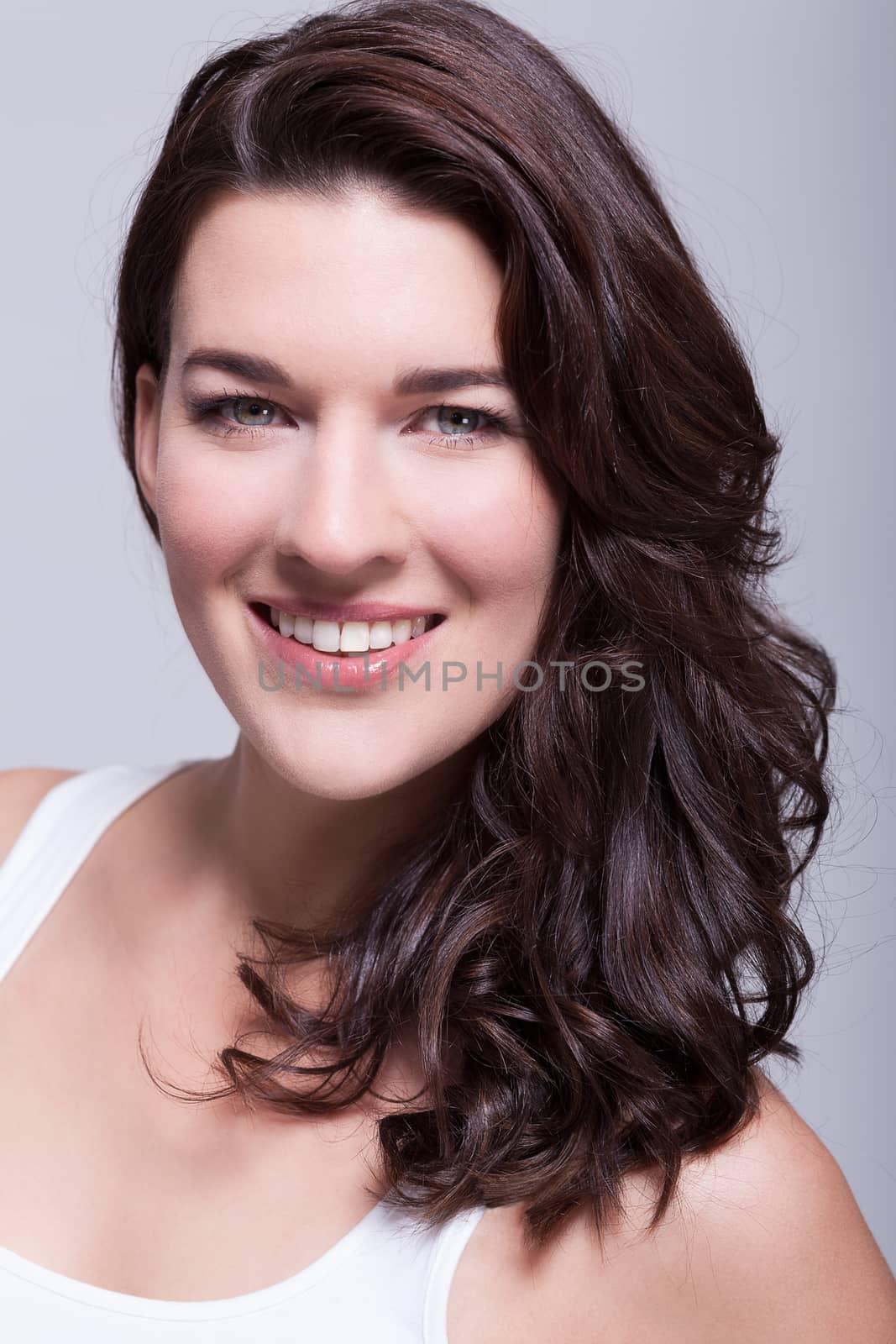 Portrait beautiful woman with dark hair smiling in the camera on grey background
