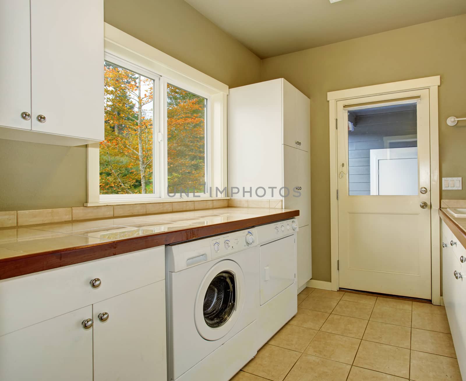 Laundry room with cabinets, tile counters, washer, and dryer.
