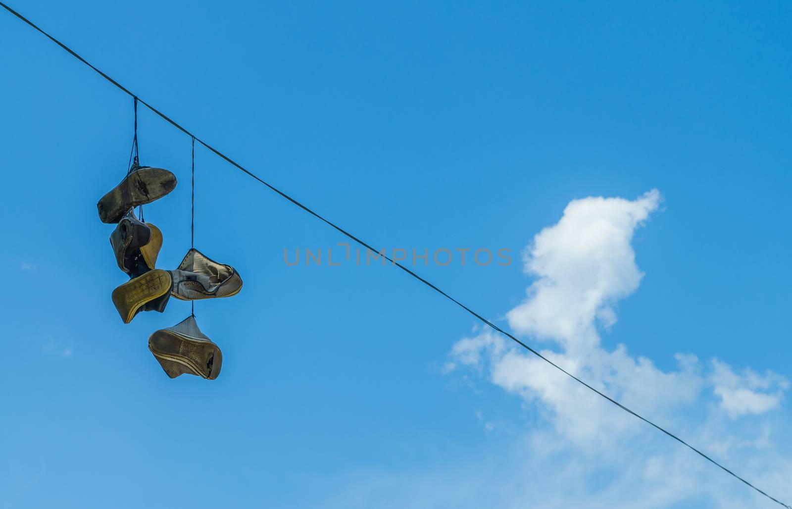 old shoes hanging on the high-voltage wire on blue sky backgroun