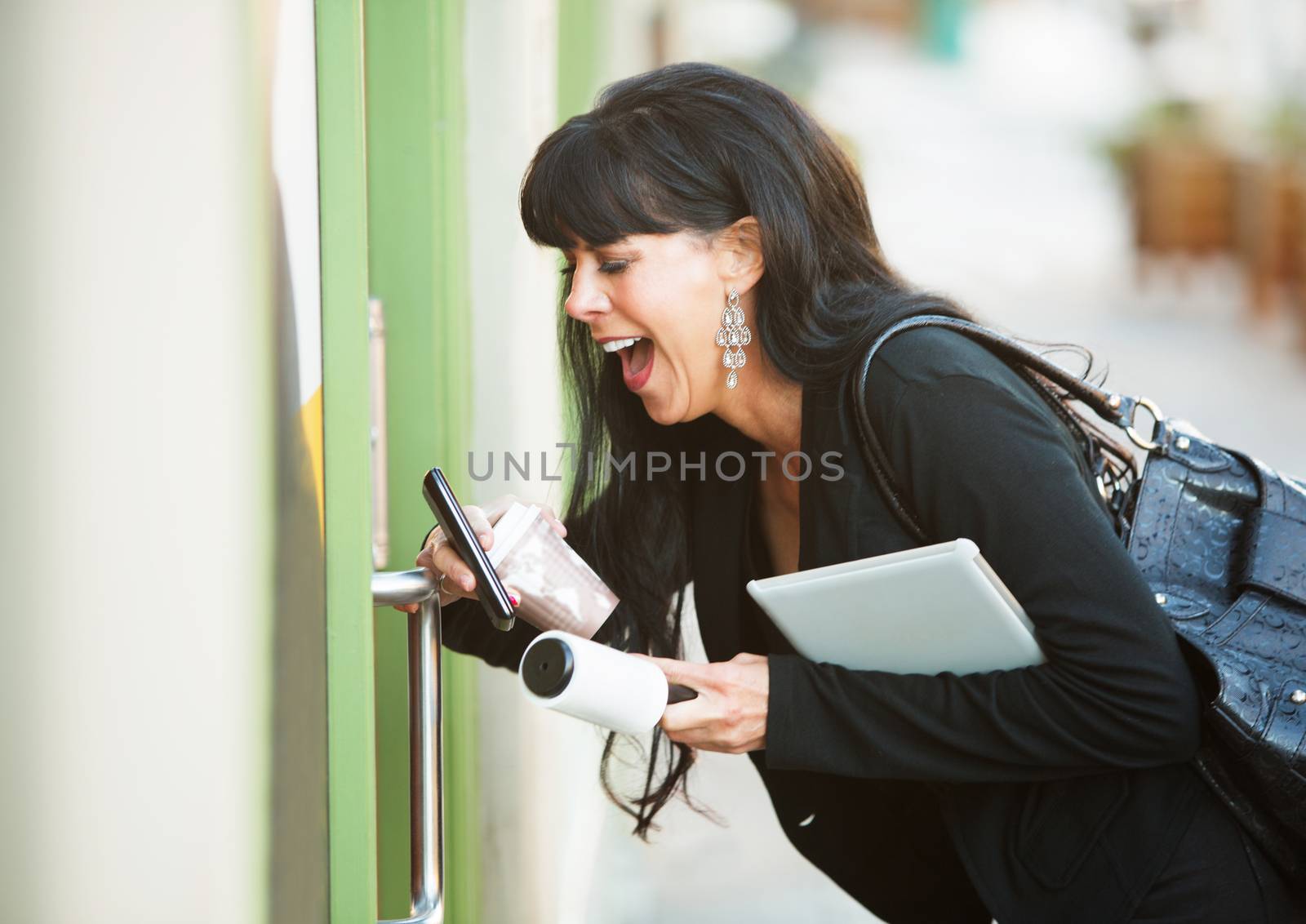 Attractive woman with her hands full attempting to open a door