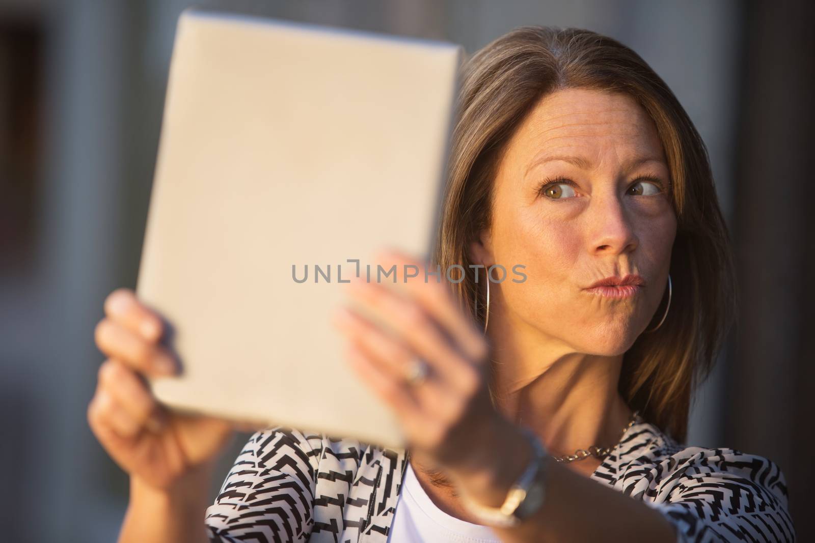 Conceited European female puckering lips at tablet computer