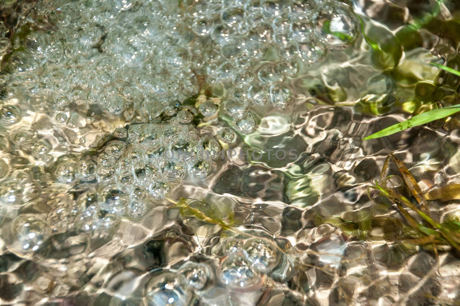 background of pebbles seen through rippling water  by alexx60