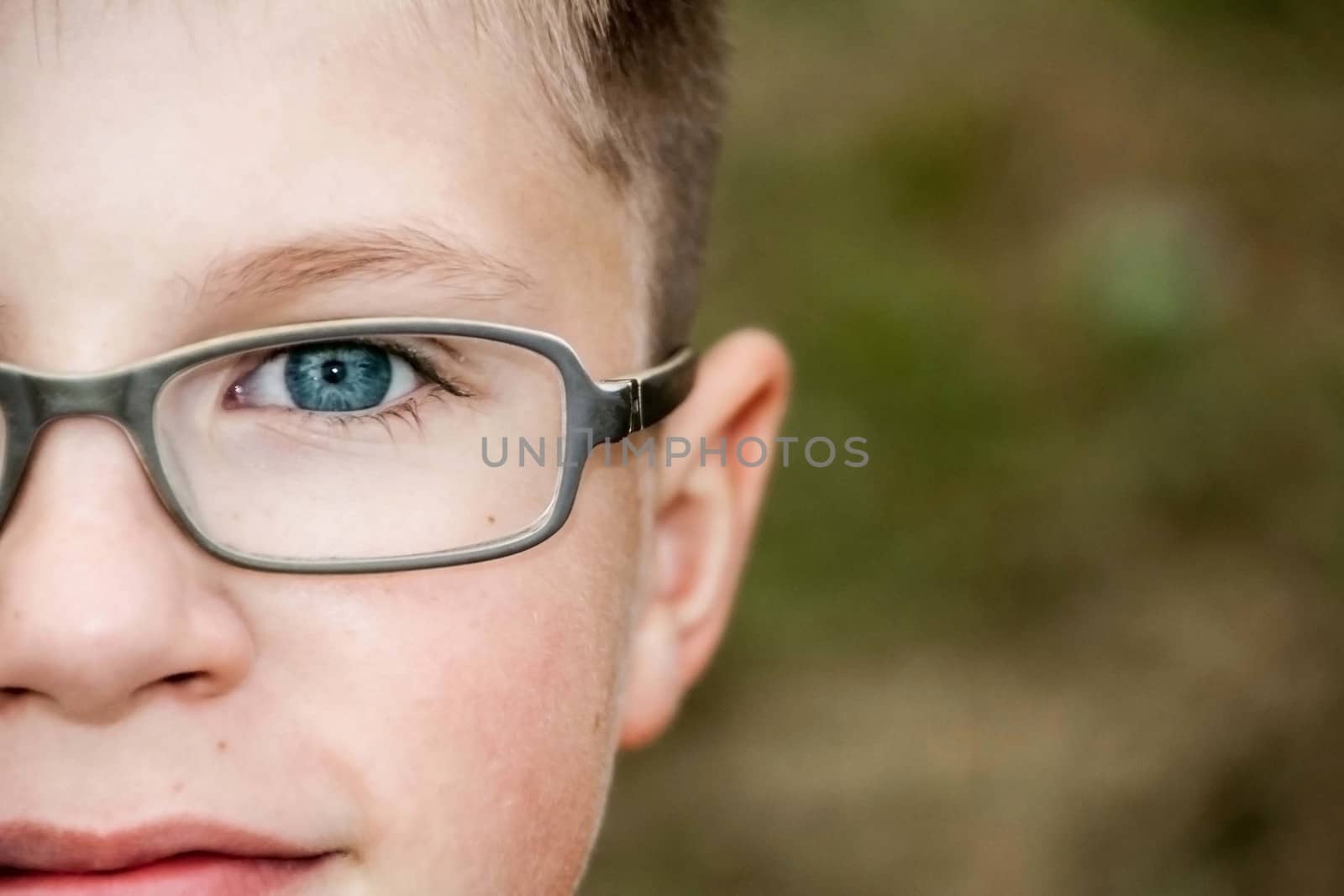 half of the face of a blue-eyed boy with glasses