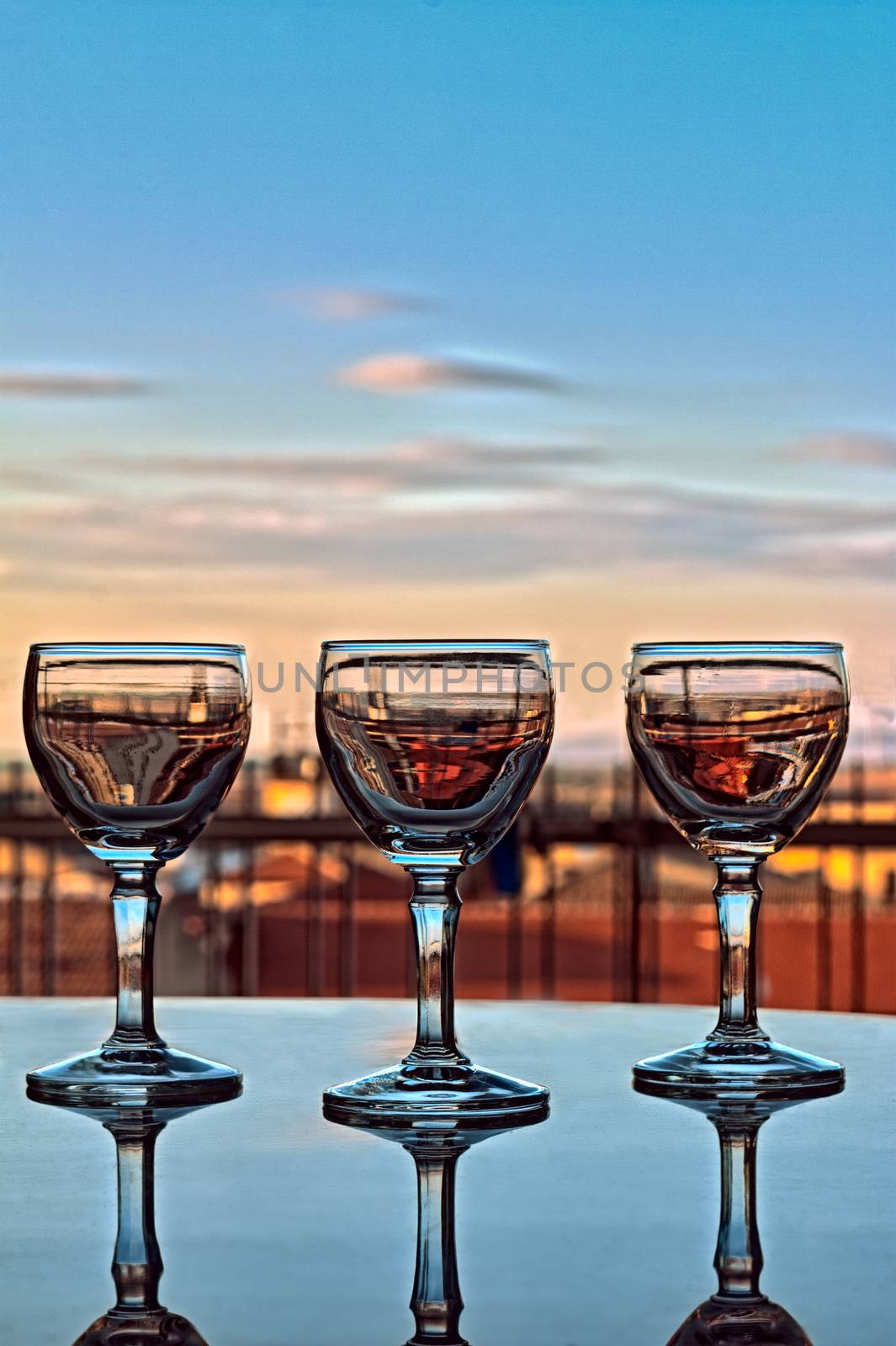 Three liqueur glasses reflected on the table at sunset
