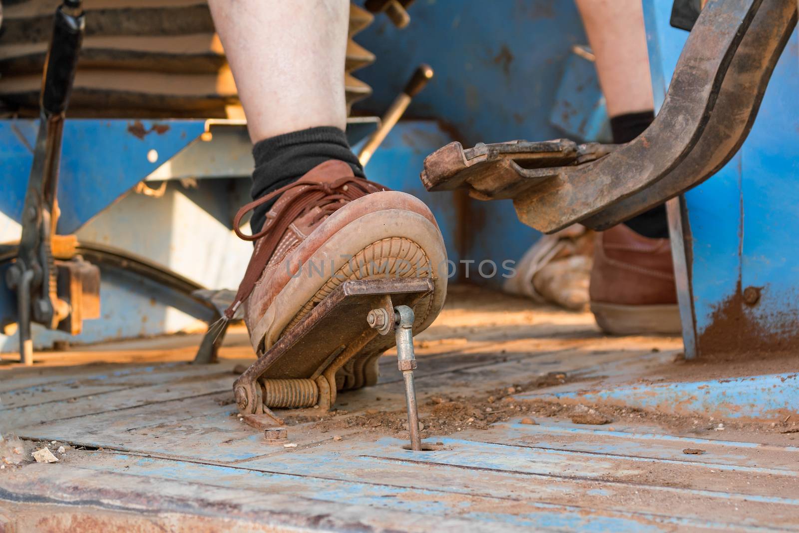 Human foot on the pedal of a tractor