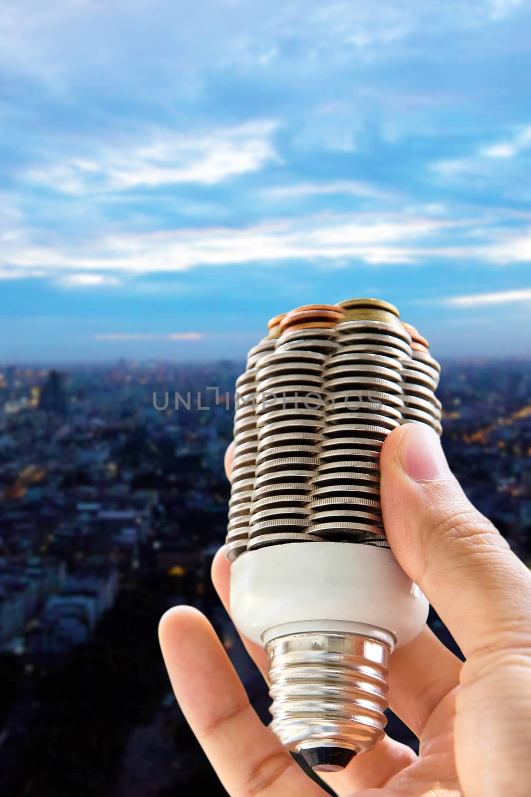 hand holding light bulb and cityscape background, eco energy concept