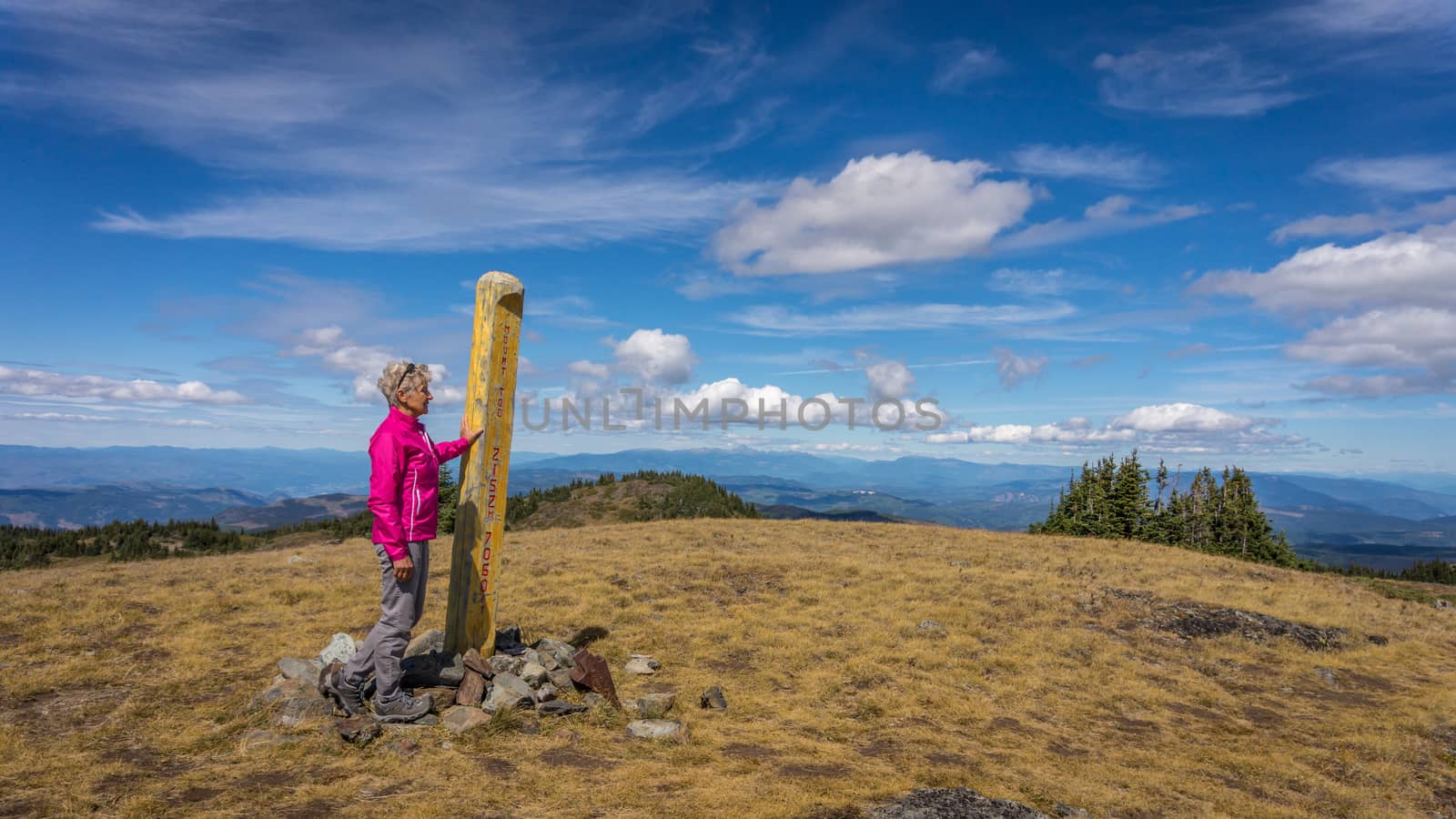 A senior woman reaching the summit of Tod Mountain in the Sushwap Highlands of central British Columbia, Canada. The summit at just over 7000 feet and it looks like one is on top of the world