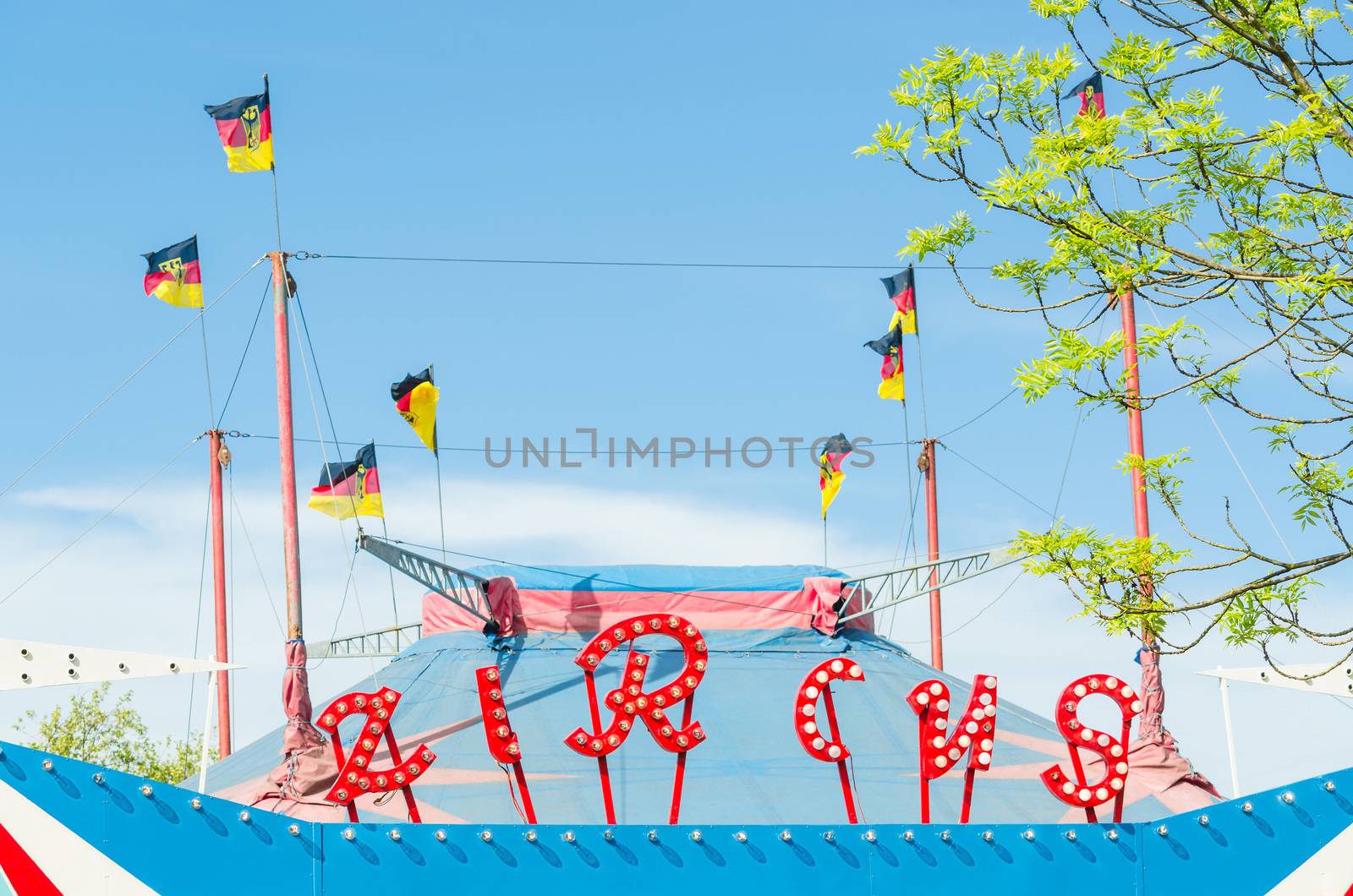 Beautiful colorful circus tent with flags in front of a bright blue sky.
