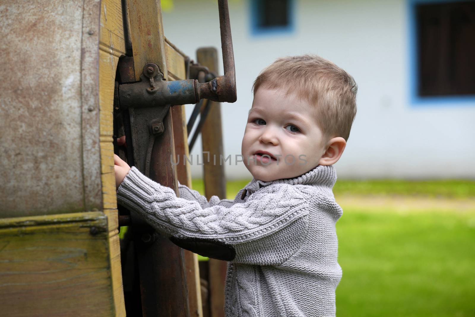 2 years old curious Baby boy managing with old agricultural Machinery