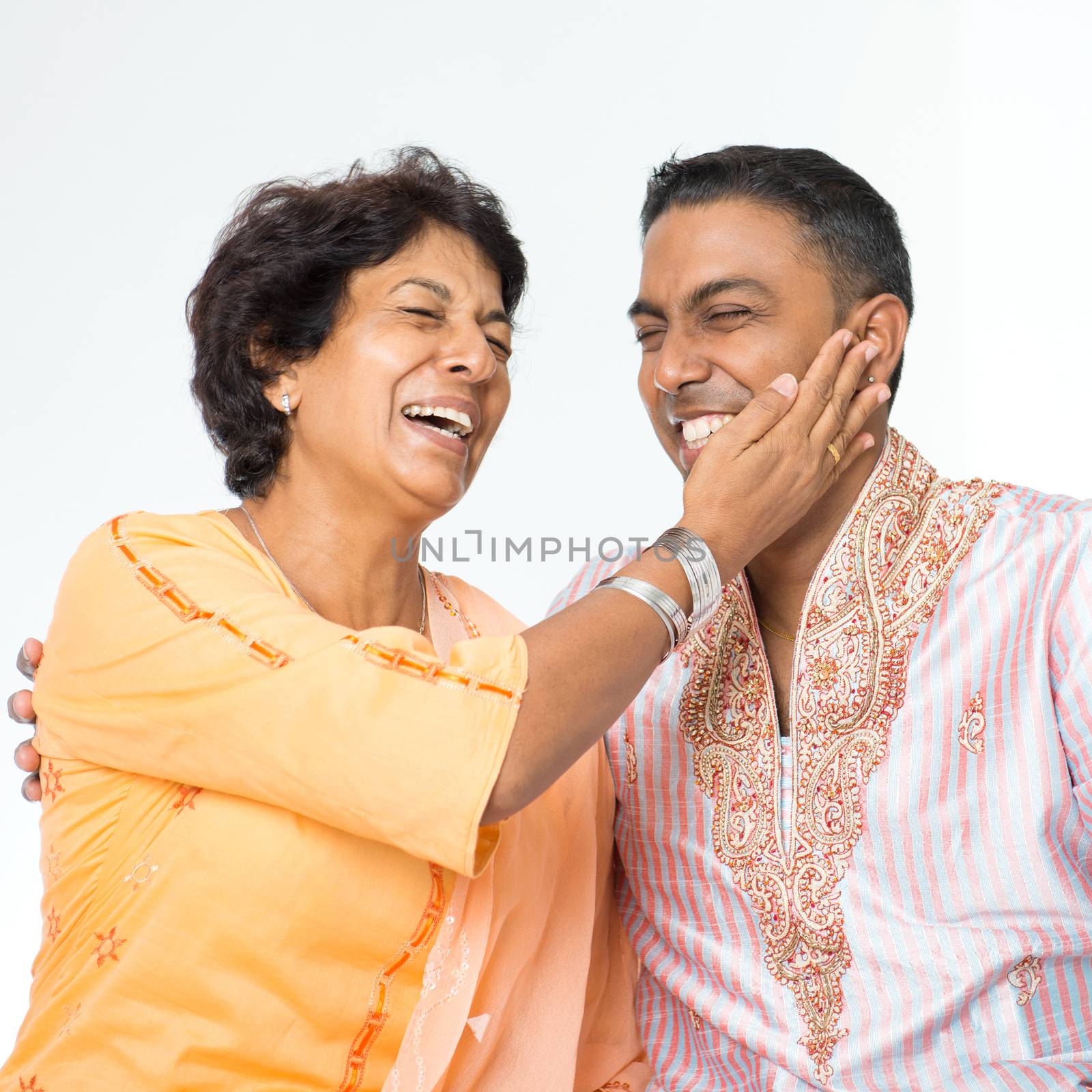 Portrait of happy Indian family having fun conversation at home. Mature 50s Indian mother and her 30s grown son.