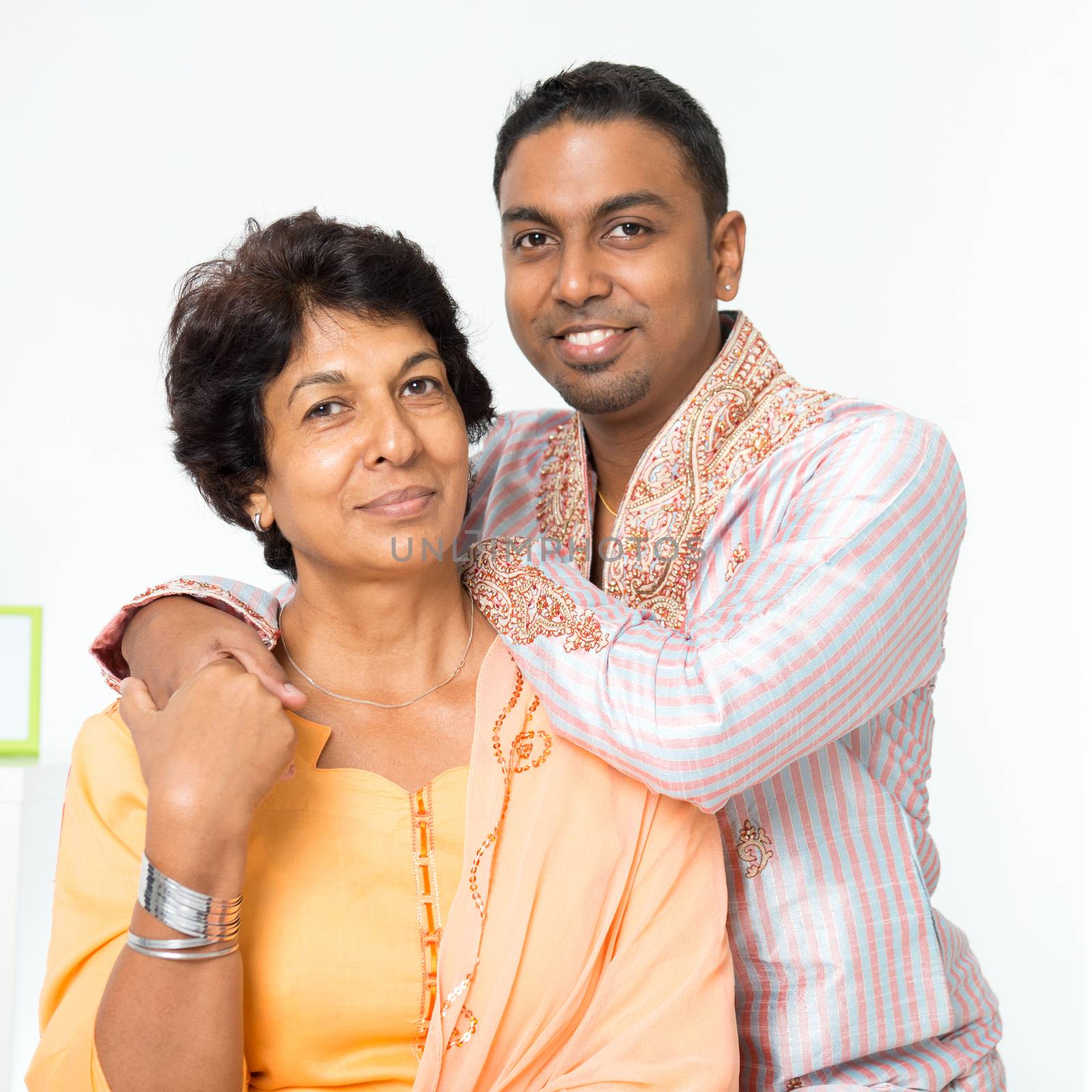 Portrait of beautiful Indian family at home. Mature 50s Indian mother and her 30s grown son.