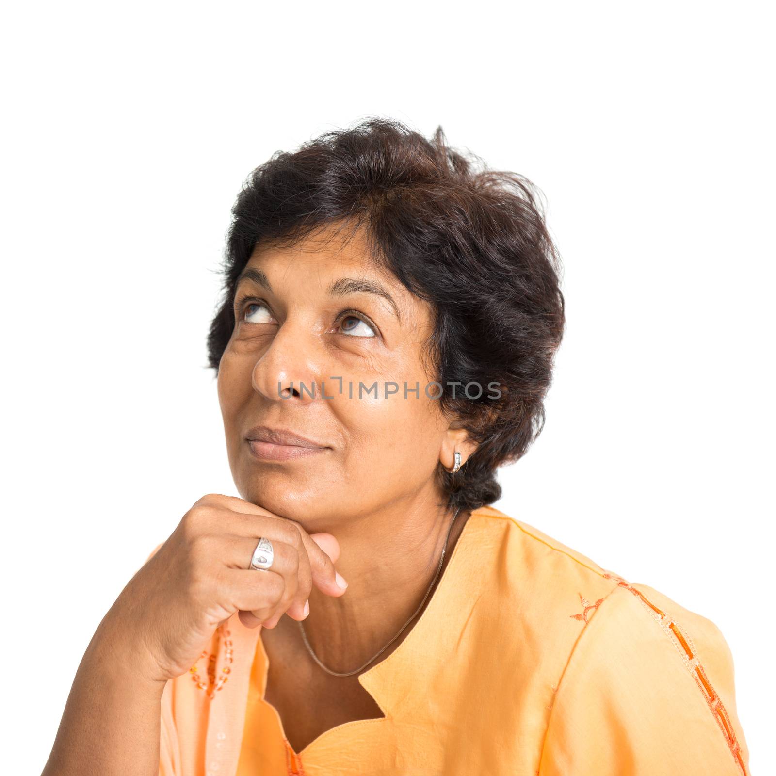 Portrait of a 50s Indian mature woman smiling and looking up having a thought, isolated on white background.