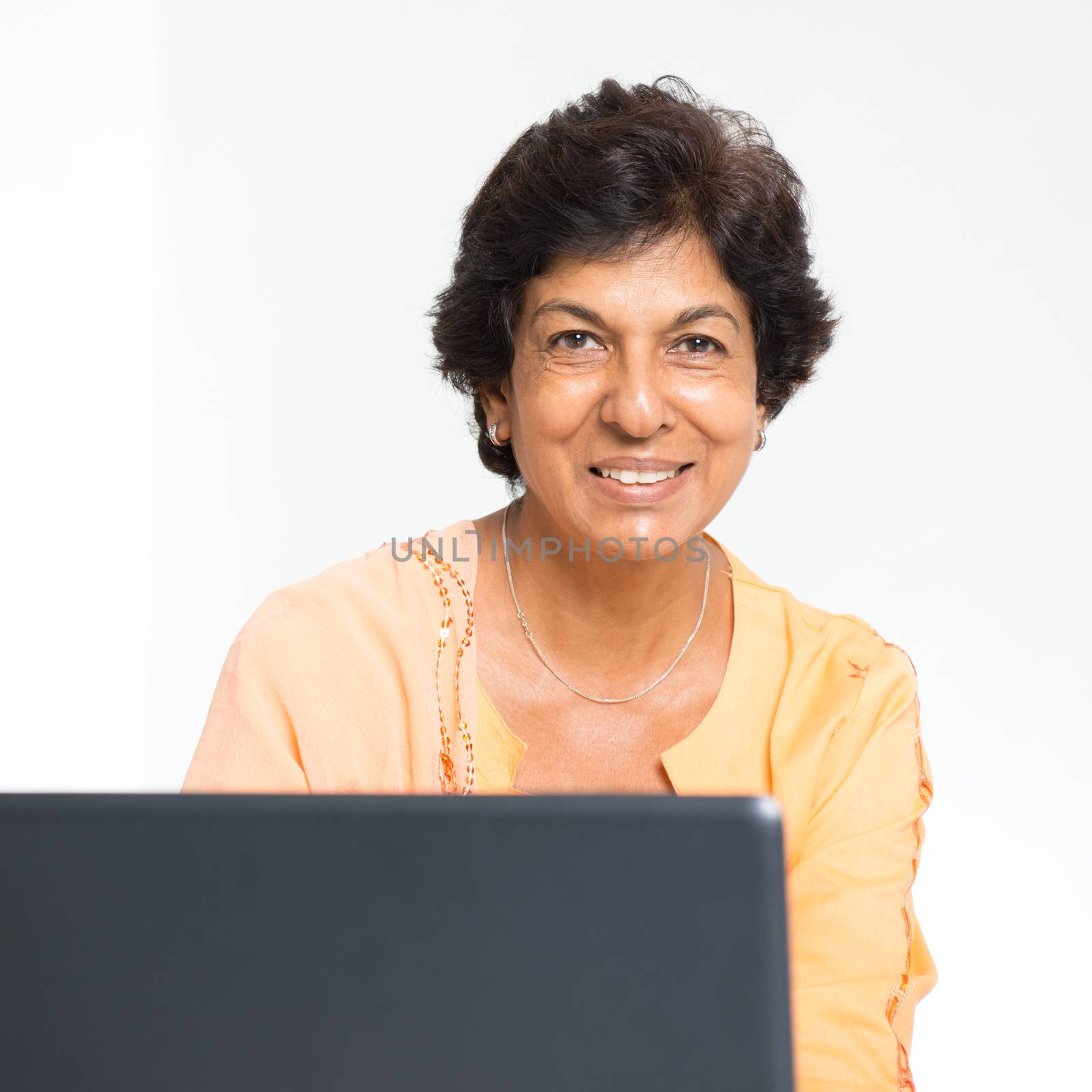 Elder people and modern technology concept. Portrait of a 50s Indian mature woman using internet at home. Indoor senior people living lifestyle.