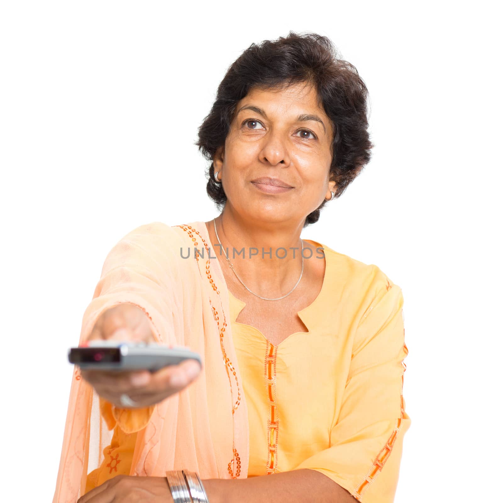 Portrait of a 50s Indian mature woman watching tv and hand holding remote control changing channel, isolated on white background.
