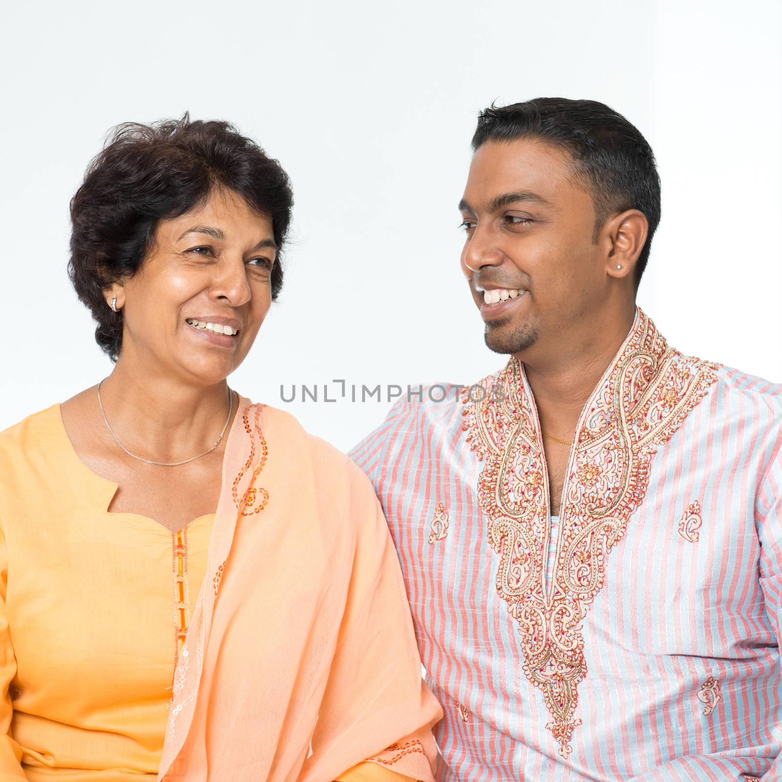 Portrait of happy Indian family communicating at home. Mature 50s Indian mother and her 30s grown son.