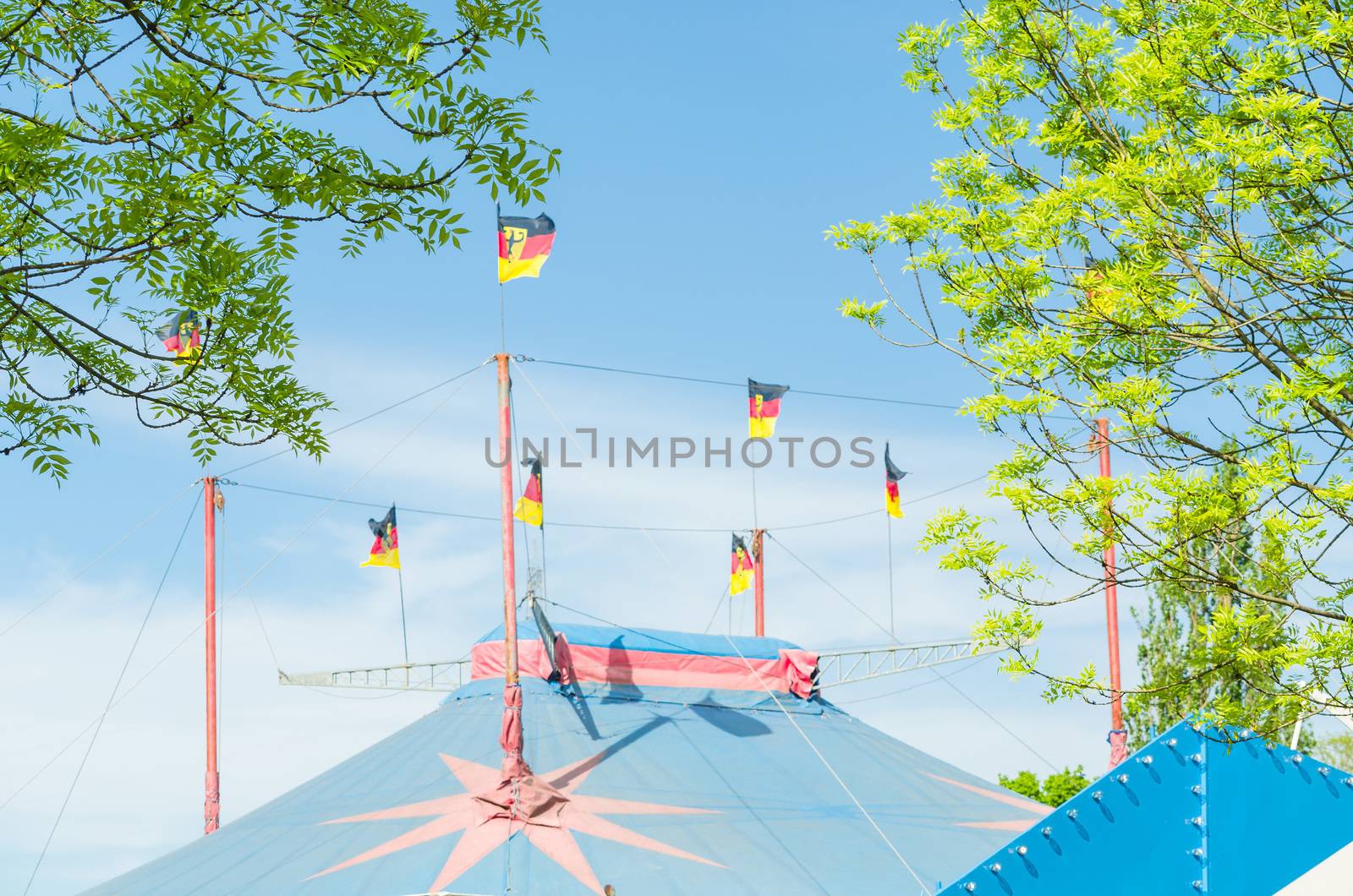 Beautiful colorful circus tent with flags in front of a bright blue sky.
