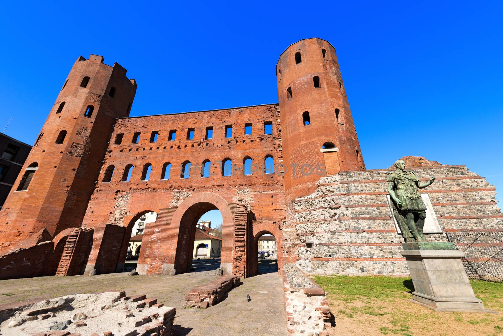 Roman statue of Julius Caesar and ancient ruins of Palatine Towers in Torino, Piemonte, Italy