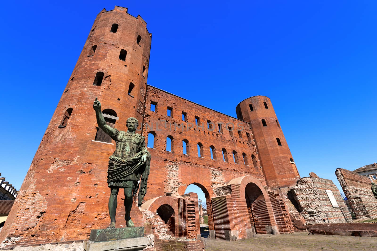 Roman statue of Gaius Octavius Thurinus and ancient ruins of Palatine Towers in Torino, Piemonte, Italy