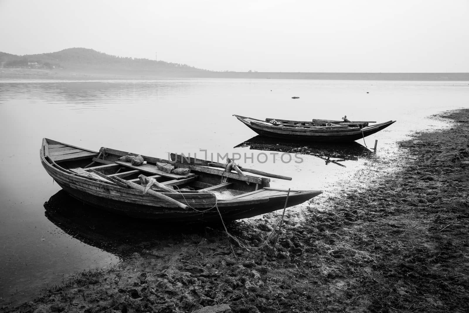 Rural Indian fishing boats tied at the shore of a river at sunset 