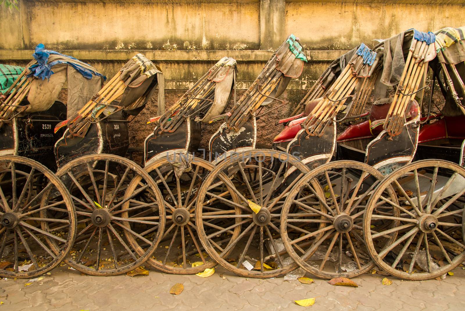 Side view of hand pulled cart rickshaws parked together.