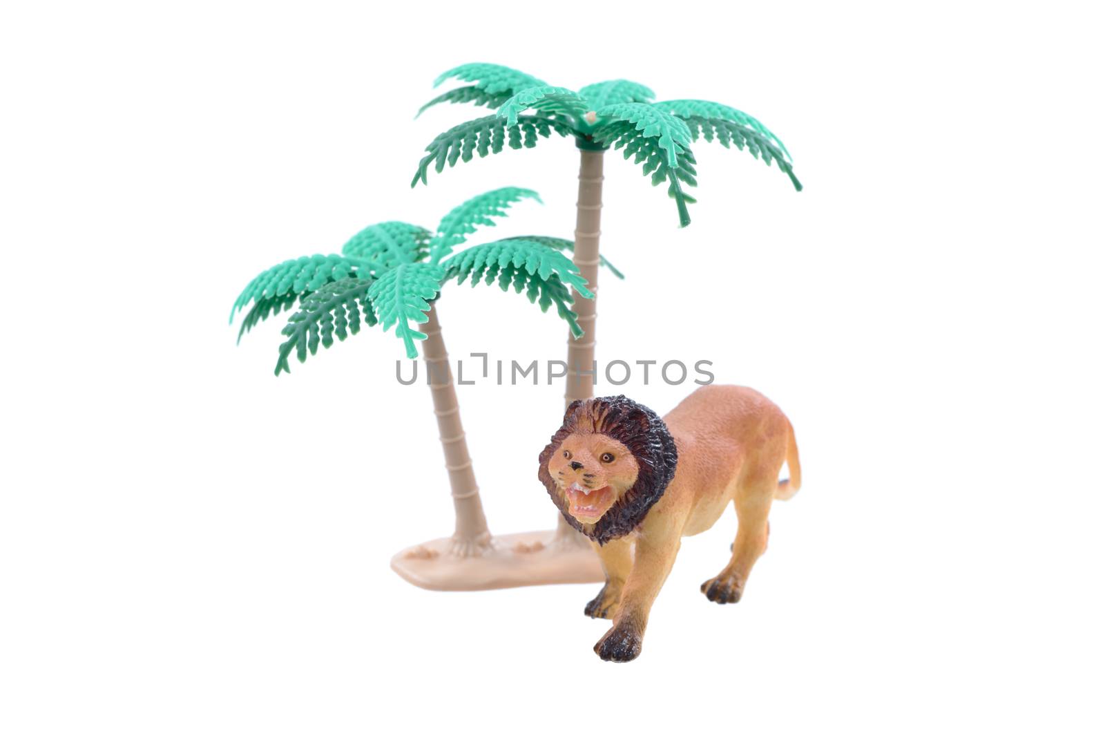 A small toy lion with trees ioslated on a white background.