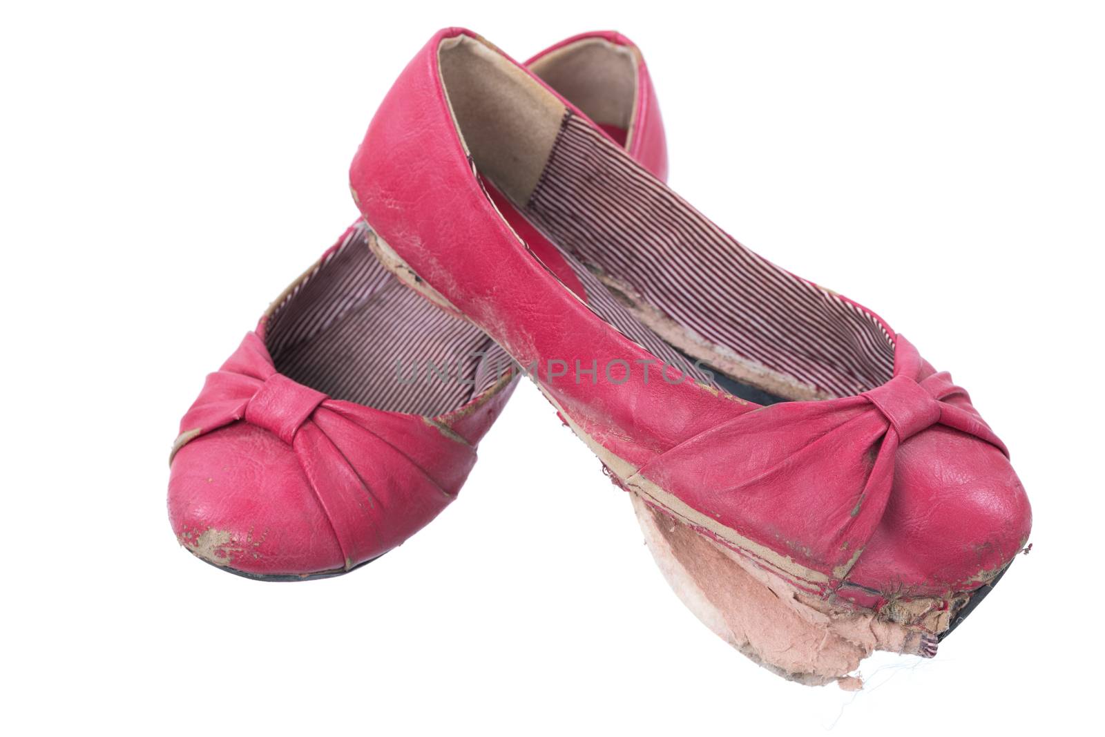 A pair of old, dirty and worn out red women's flats isolated on a white background.
