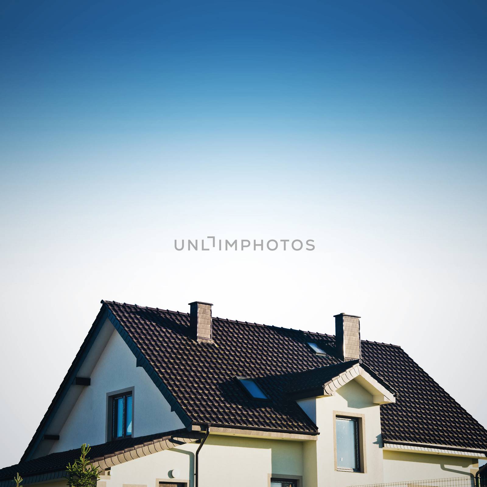 Blue roof of new detached house against blue sky.