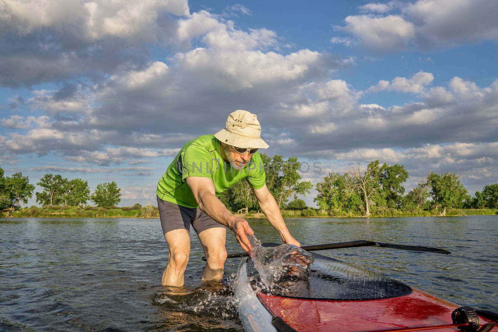 male SUP paddler with paddleboard by PixelsAway