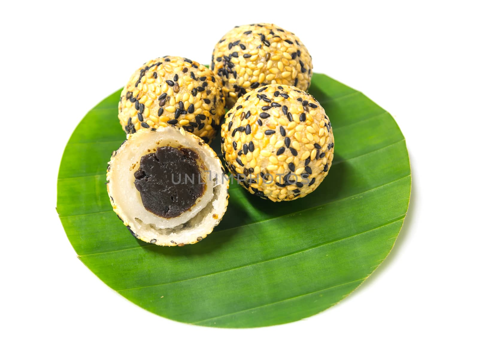 deep fried sticky rice balls with black and white sesame, preserved jujube center filled on round shape banana leaf