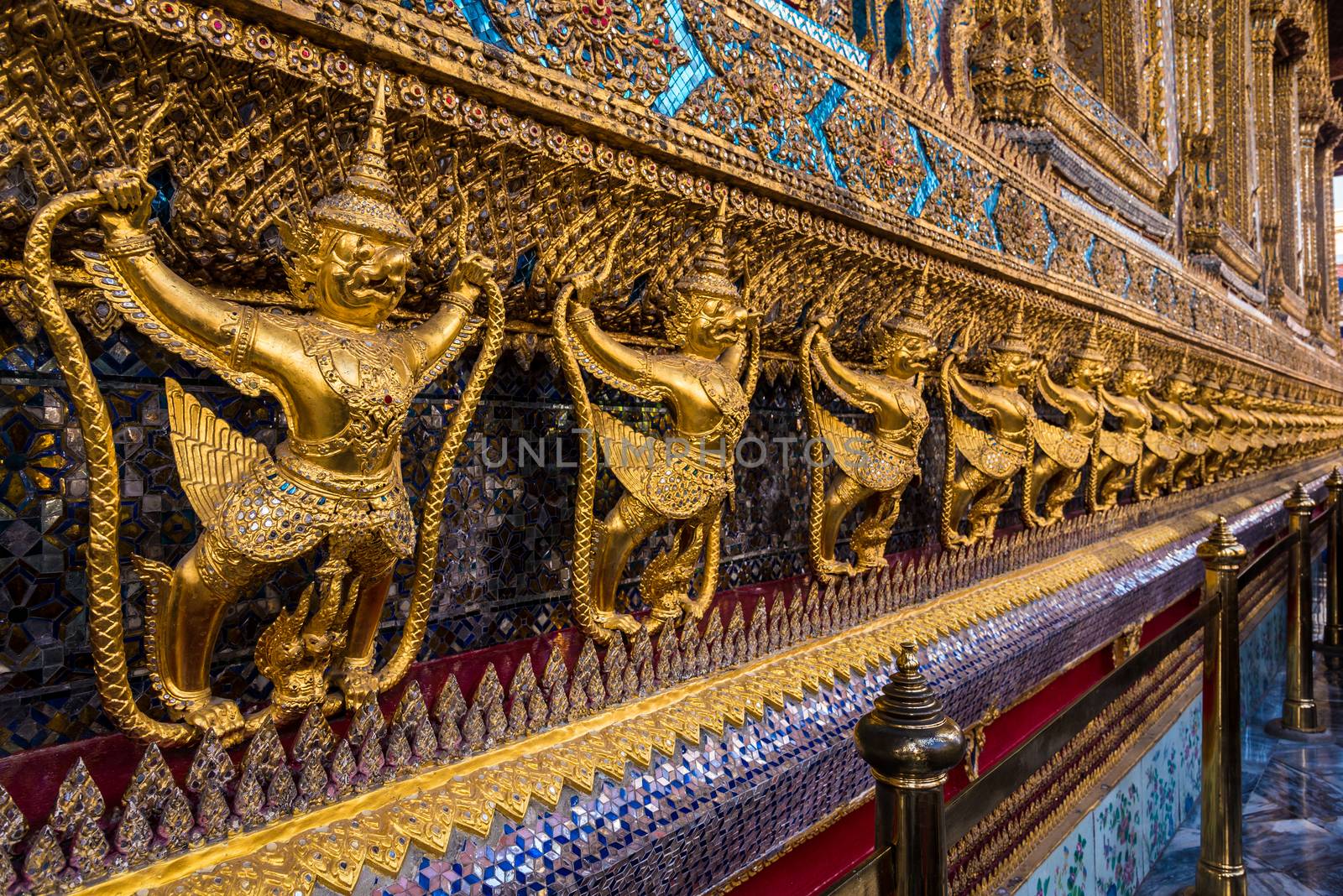 Architecture of emerald buddha temple with golden warriors guarding the temple in Bangkok, Thailand.