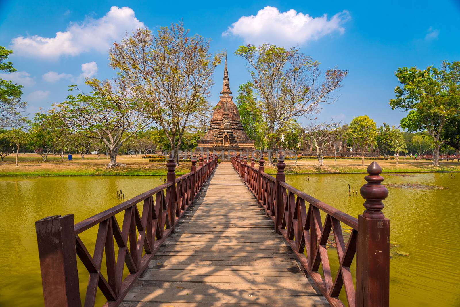 Wooden bridge leading to ancient Stupa at Wat Sa Sri in Sukhothai Historical Park, Thailand.