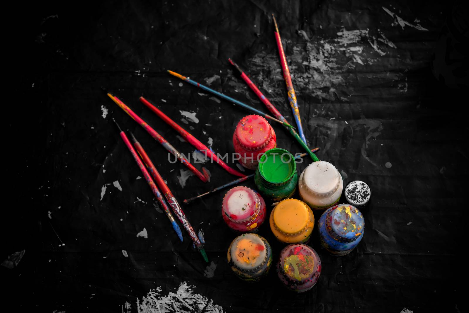 Assorted brushes and colors of artist palette over black cloth.