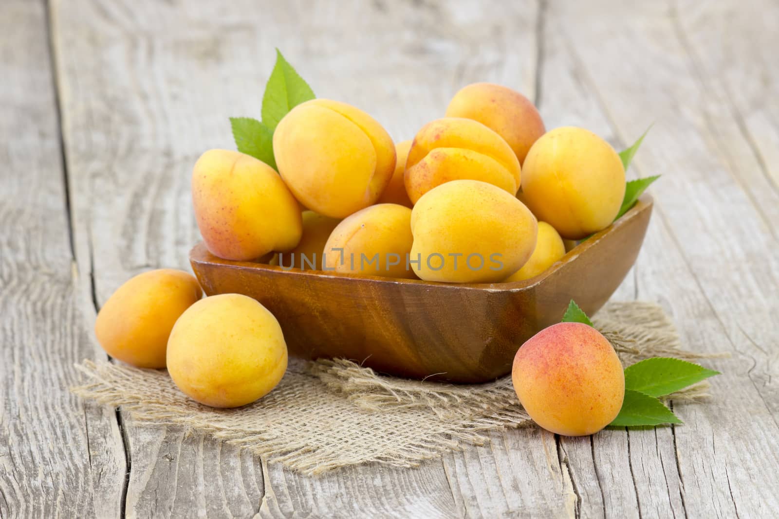 fresh apricots in a bowl on wooden background