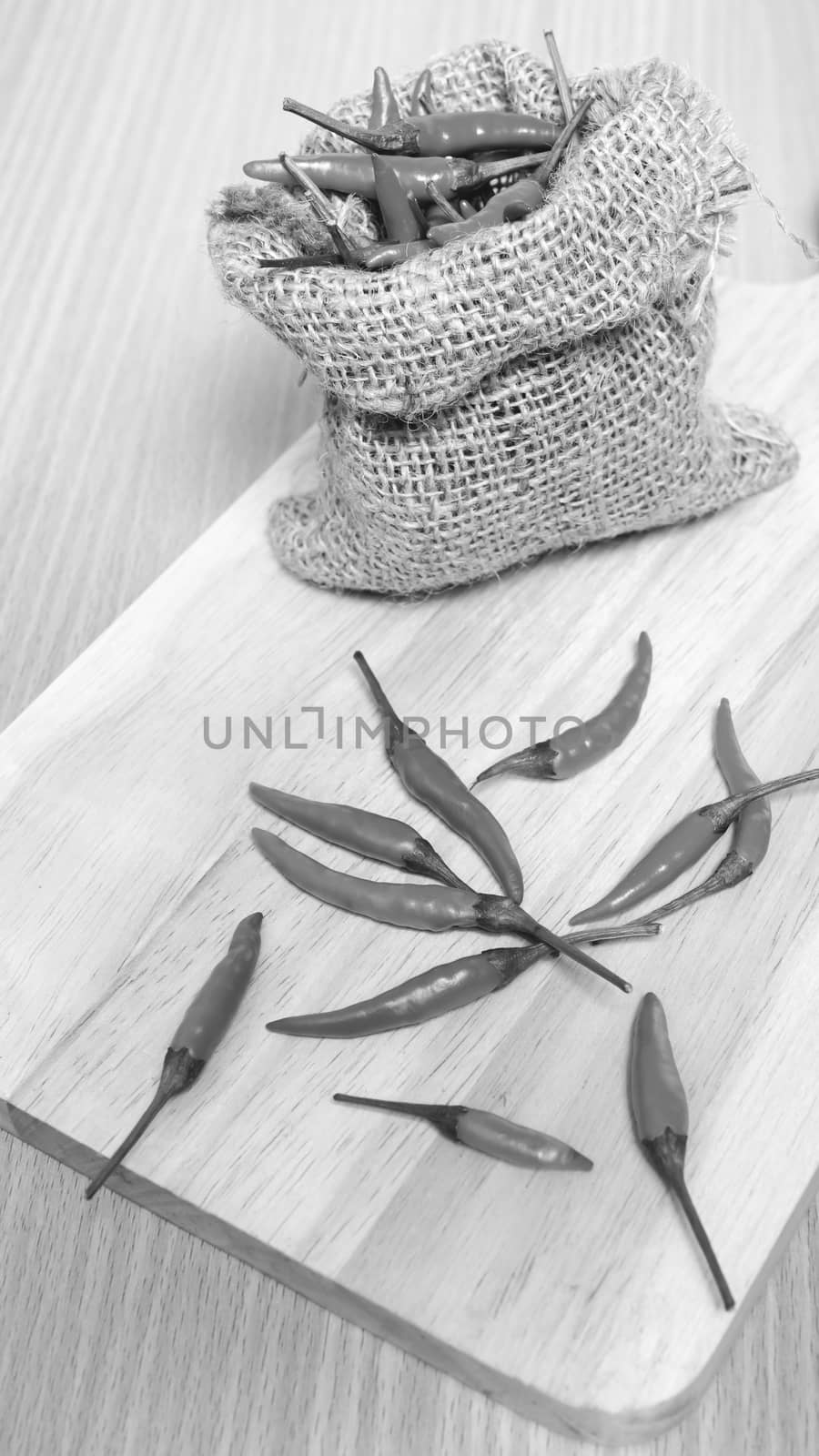 red chili peppers on cutting board over wood table background black and white tone color style