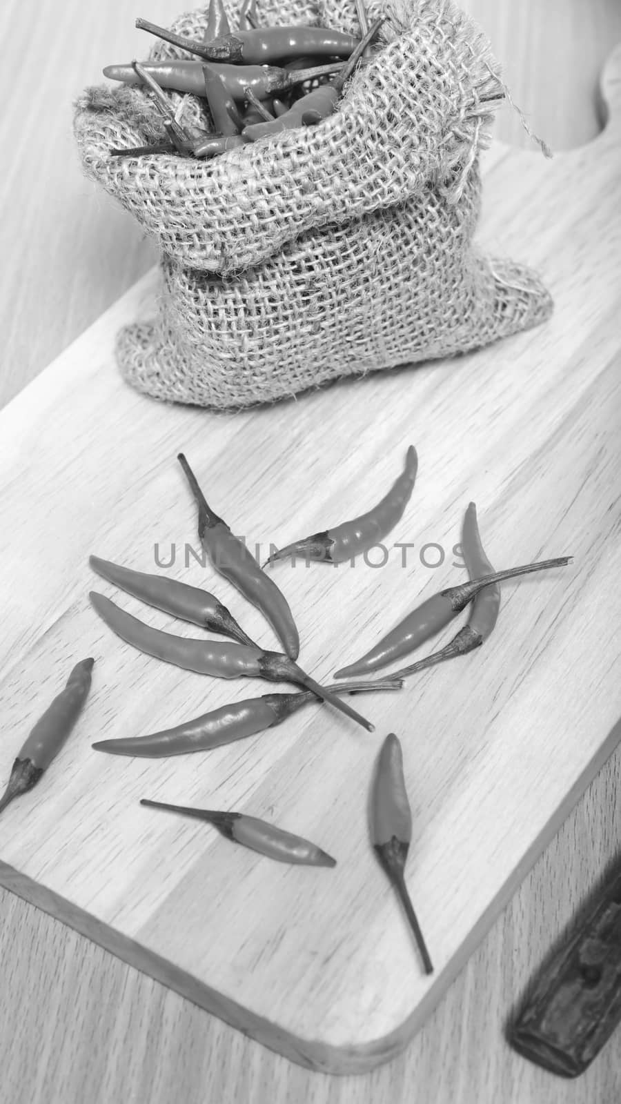 red chili peppers on cutting board over wood table background black and white tone color style